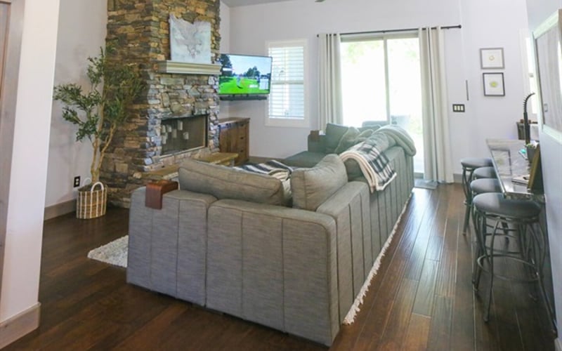 LoveSac couch in the great room backing up to the kitchen with direct views of the golf course, smart TV, and stone fireplace with LED candles